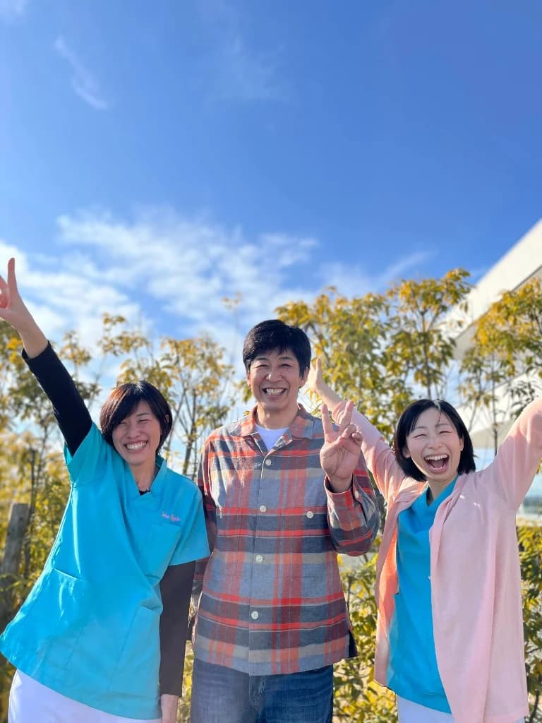屋外で笑顔でポーズをとるスタッフの写真