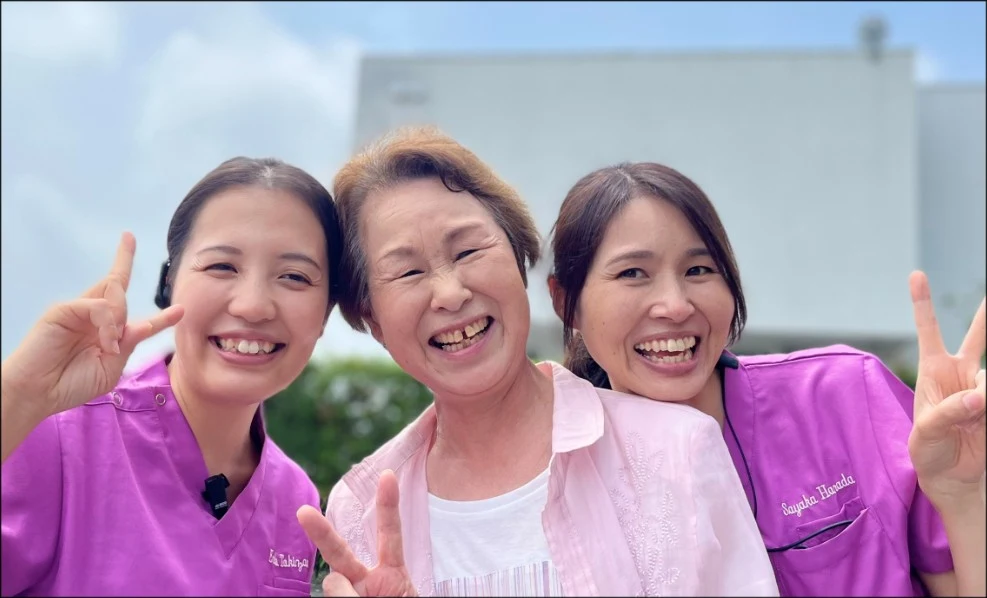 ピースサインで笑う患者さんとスタッフ